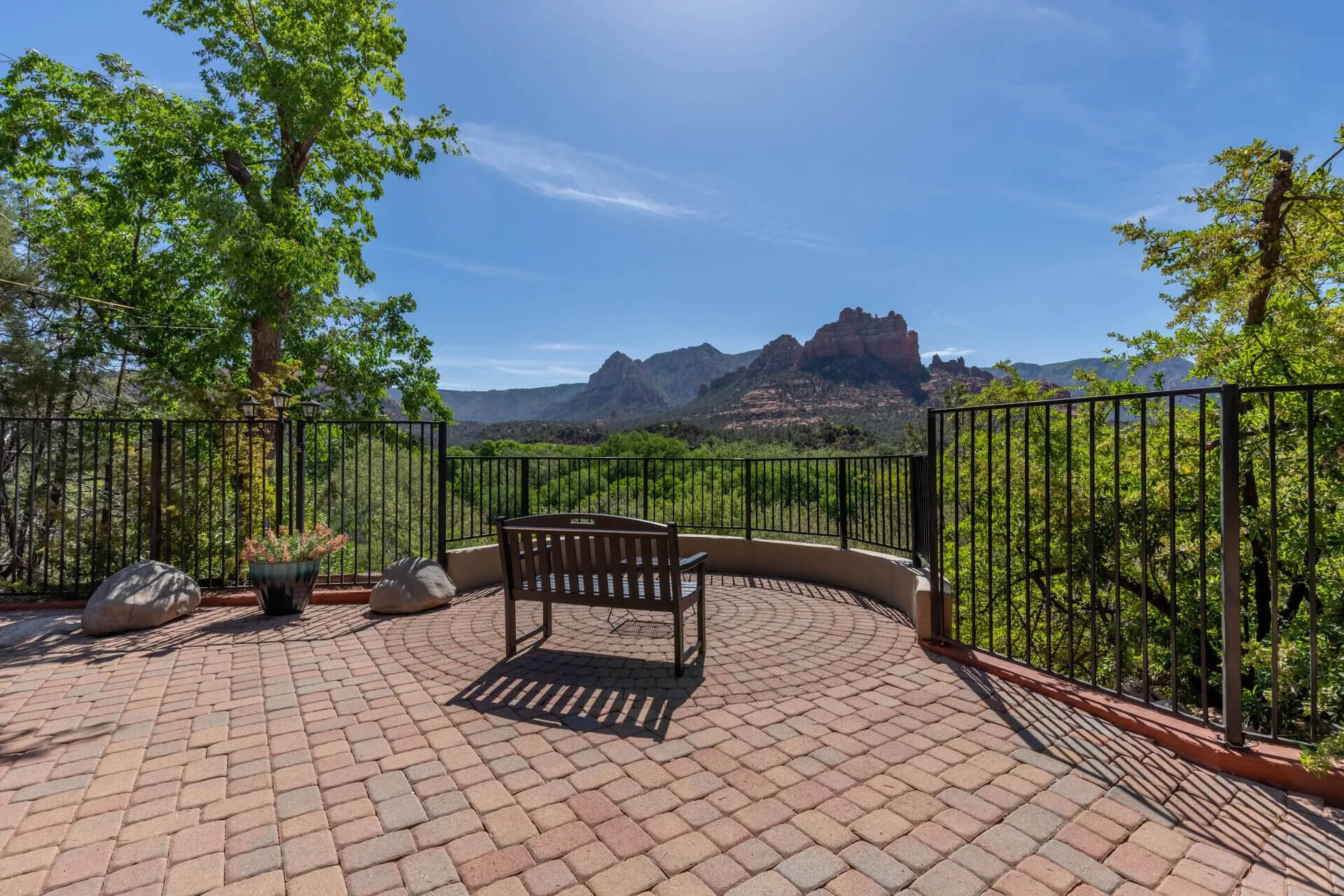 A brick patio with a metal railing and a view of mountains in the distance.