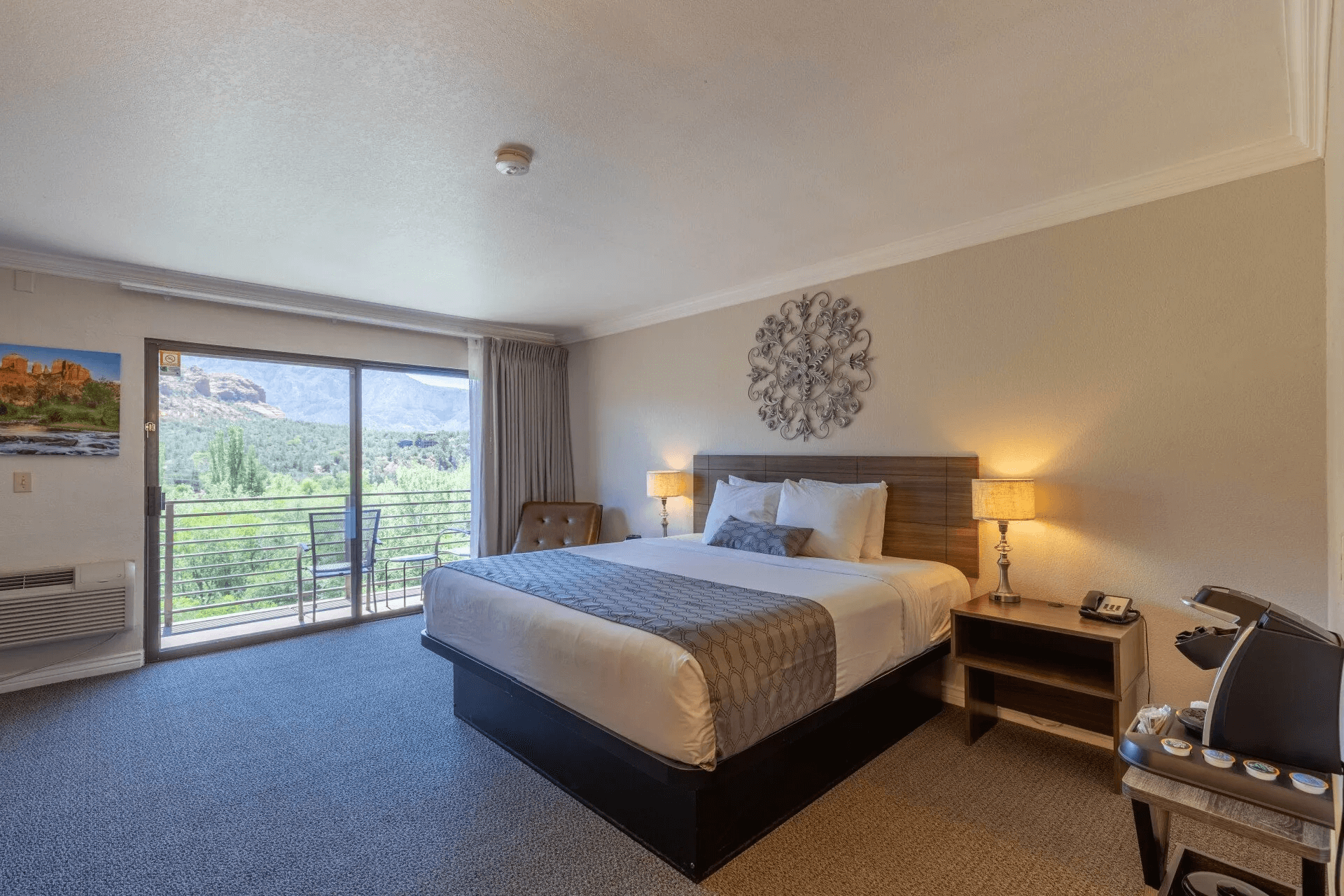 A hotel room with a large bed, balcony, and mountain view.
