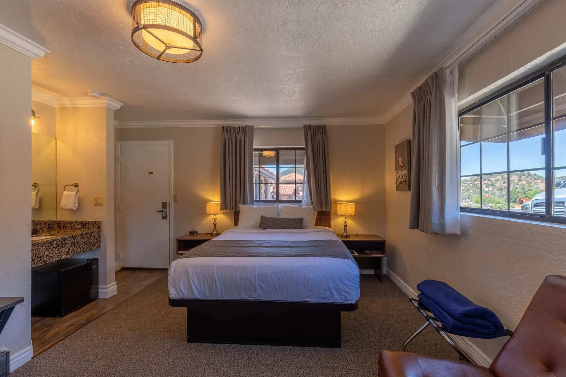 A hotel room with a bed, window, and bathroom.